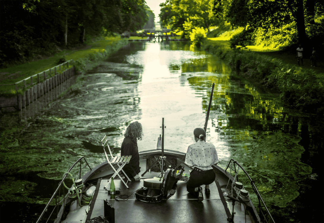 Photo de deux artistes de dos sur une péniche.