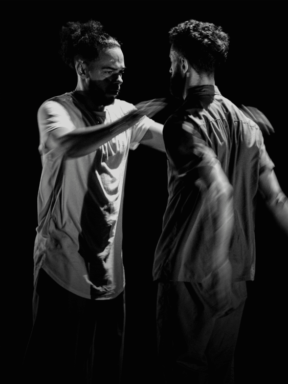 Photo en noir et blanc des deux artistes en mouvement.