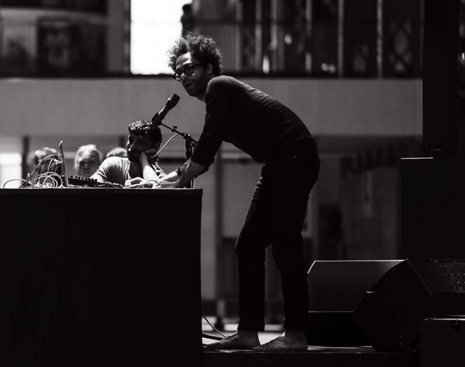 Photo en noir et blanc. Homme parlant à un micro durant le spectacle Crack. Photo en noir et blanc. Homme parlant à un micro durant le spectacle Crack.