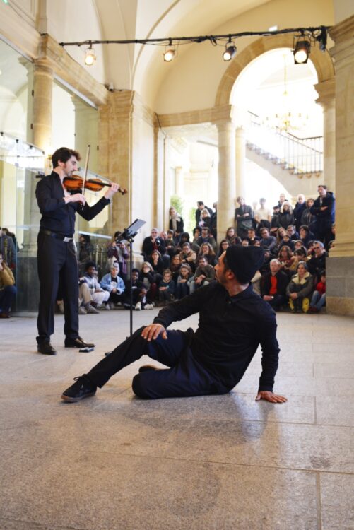 Danseur en mouvement regardant le violoniste avec spectateur en fond. Danseur en mouvement regardant le violoniste avec spectateur en fond.