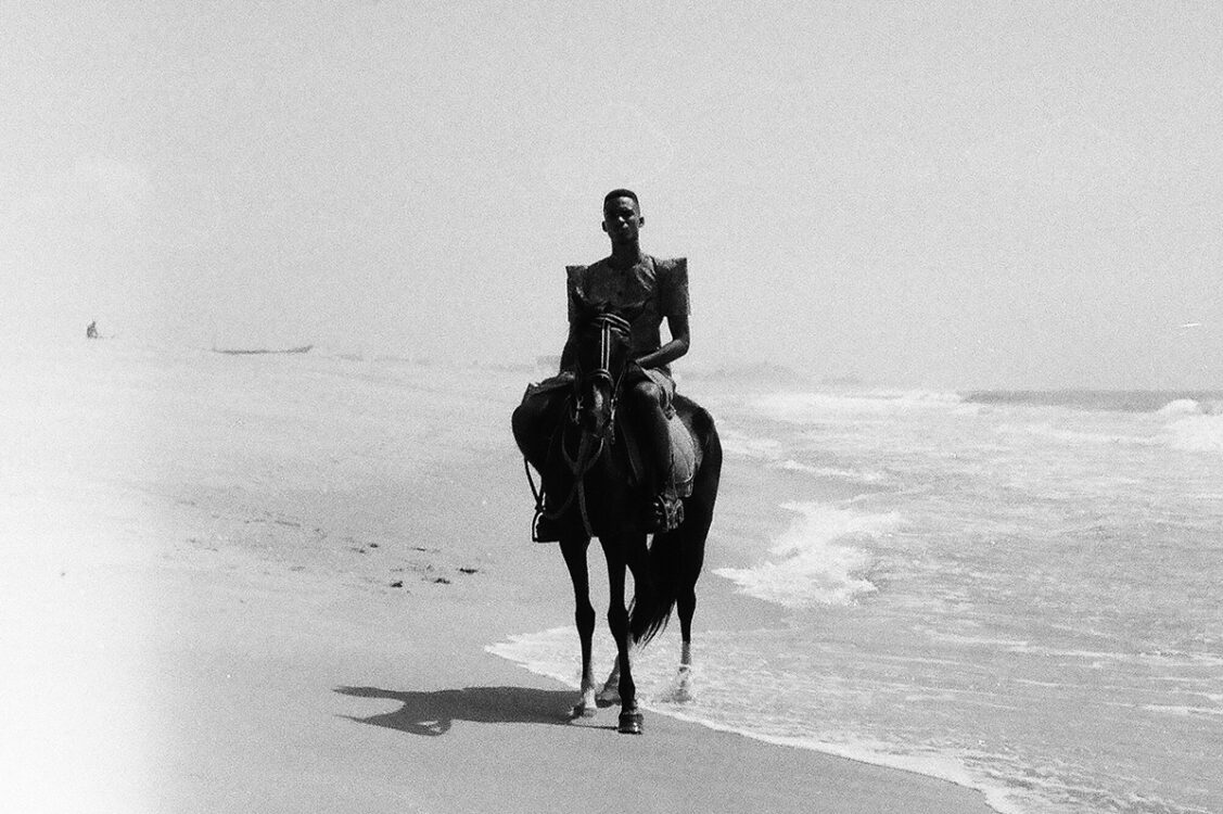 Photo en noir et blanc. Personne à cheval au bord de plage. Photo en noir et blanc. Personne à cheval au bord de plage.