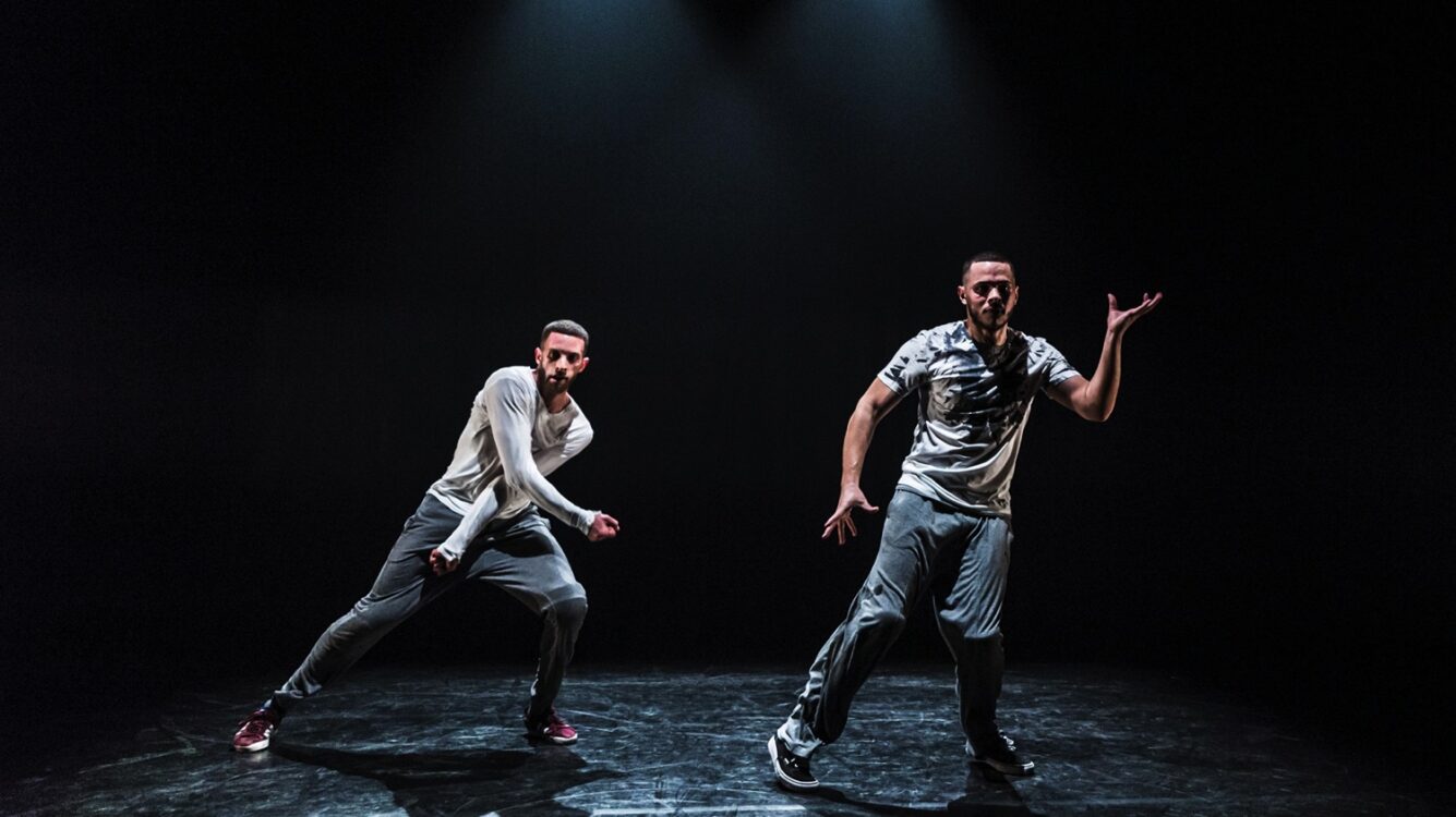Deux danseurs en mouvement avec fond noir au spectacle Dans l'arène.