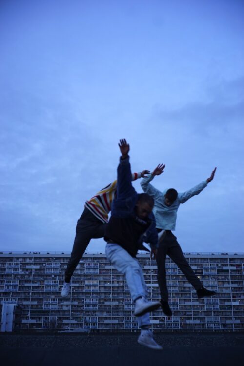 Trois danseurs en mouvement. Fond est un immeuble en large. Trois danseurs en mouvement. Fond est un immeuble en large.