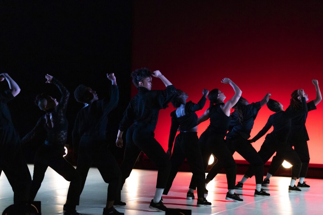 Danseuses sur scène, en mouvement. Le fond est rouge et elles sont en noir. Danseuses sur scène, en mouvement. Le fond est rouge et elles sont en noir.